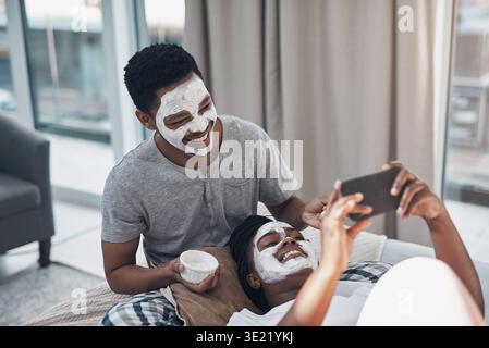 Selfie, Hautpflege und schwarzes Paar zu Hause mit Gesichtsmaske für gesunde Haut, Bindung oder Wellness. Ehe, soziale Medien und Mann mit Frau mit Foto Stockfoto