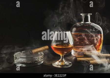 Glas Whiskey mit rauchender Zigarre und Flasche Stockfoto