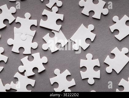 Sammlung von weißen Puzzleteilen auf grauem Hintergrund im Collage-Stil Stockfoto