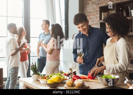 Ein multiethnisches Paar bereitet mit Freunden ein Abendessen in der Küche vor Stockfoto