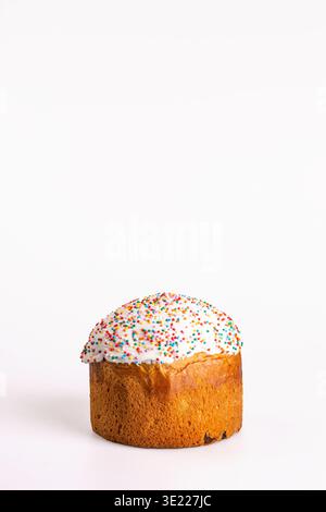 Traditionelles Osterkulich mit goldener Kruste und glänzend weißer Glasur, gekrönt mit hellen mehrfarbigen Streuseln, isoliert auf sauberem weißem Hintergrund Stockfoto