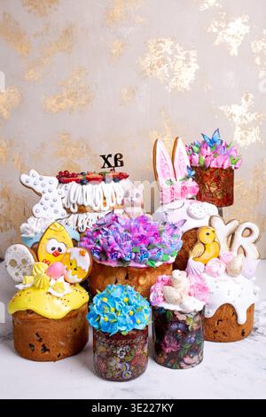 Dekorative Osterkuchen mit Glasur, Blumen, Hasenohren und Küken in festlicher Komposition. Helle Frühlings-Dessertszene symbolisiert Celebra Stockfoto