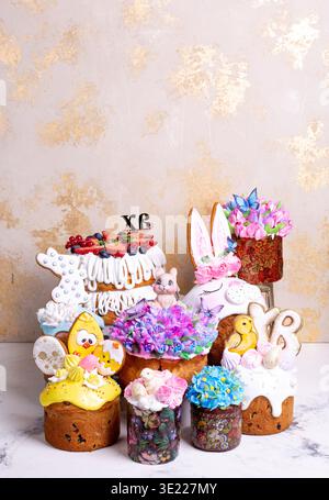 Dekorative Osterkuchen mit Glasur, Blumen, Hasenohren und Küken in festlicher Komposition. Helle Frühlings-Dessertszene symbolisiert Celebra Stockfoto