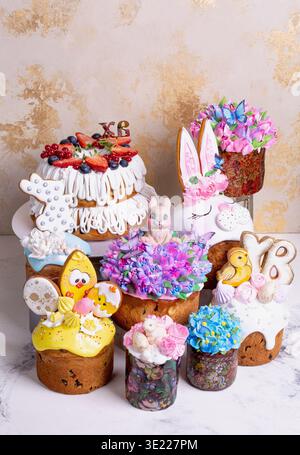 Dekorative Osterkuchen mit Glasur, Blumen, Hasenohren und Küken in festlicher Komposition. Helle Frühlings-Dessertszene symbolisiert Celebra Stockfoto
