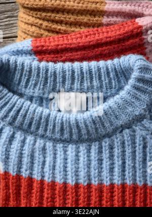 Farbenfrohe Strickpullover mit gerippter Struktur in Rot, Blau und Braun auf Holzoberfläche. Deutschland Stockfoto