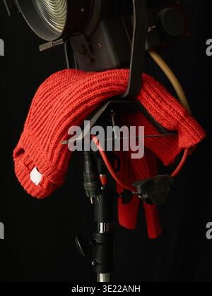 Ein roter Strickpullover, der über einer Bühnenleuchte auf schwarzem Hintergrund liegt. Deutschland Stockfoto