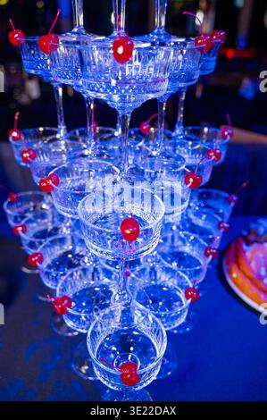 Kristall-Champagnercoupés, dekoriert mit roten Kirschen in einer gestuften Anordnung. Konzept von Luxus Cocktailbar Service, Vintage Party Ästhetik und so Stockfoto