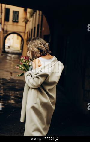 Frau, die Bouquet in der Gassen-Szene hält Stockfoto