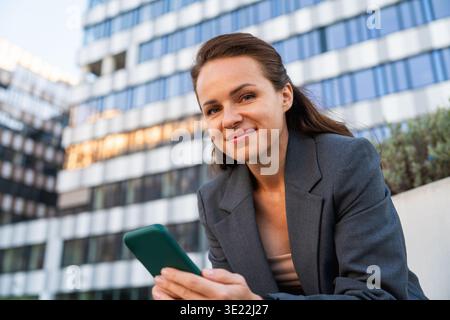 Porträt einer lächelnden Geschäftsfrau draußen auf einer Stadtstraße. Stockfoto