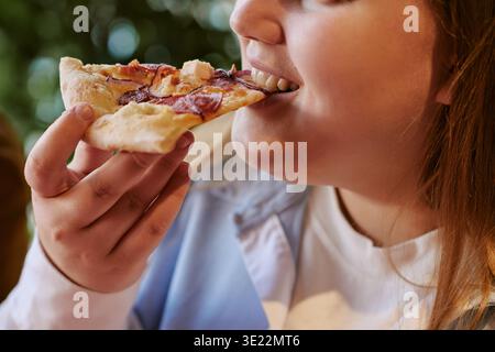 Eine junge Frau genießt Pizza im Freien Stockfoto