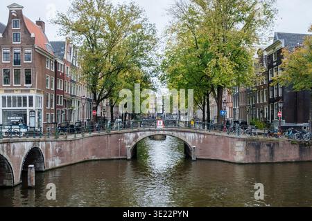 Amsterdam, Niederlande - 10.06.2025: Keizersgracht-Kanal in Amsterdam mit Brücken, Häusern und Bäumen an einem bewölkten Herbsttag. Stockfoto