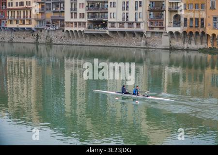 Zwei Personen, die auf dem Fluss Arno mit historischen Gebäuden im grünen Wasser schweben, Florenz, Italien. Stockfoto