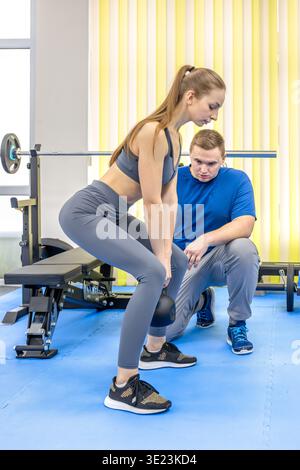 Zwei Menschen in der Reha, Frau hebt die Kesselglocke mit ärztlicher Anleitung. Wiederherstellung der Festigkeit. Stockfoto