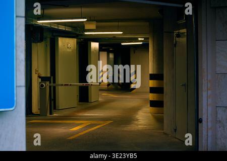 Blick auf den Eingang einer Tiefgarage mit einem Absperrtor und gelben Richtungsmarkierungen auf dem Betonboden Stockfoto
