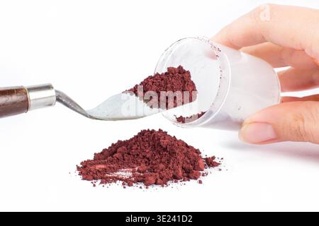 Eine braune Pulversubstanz wird ordentlich auf einer sauberen weißen Oberfläche aufgestapelt, was auf ihr Potenzial für verschiedene kulinarische Anwendungen hinweist. Caput Mortuum Stockfoto