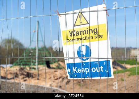 Warnung Baustelle, Schild fernhalten, an Metallzäunen vor einem Kinderspielplatz befestigt. Stockfoto