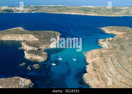 Aus der Vogelperspektive schlängelt sich das türkisfarbene Wasser um felsige Felsvorsprünge und Sandstrände und schafft einen atemberaubenden Kontrast der Farben in der Blue Lagoon, Malta. Stockfoto