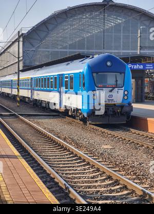 Prag, Tschechische Republik - 18. März 2026: Elektrischer Pendlerzug, der am Bahnsteig des Prager Hauptbahnhofs ankommt und Passagiere zu Fuß gehen Stockfoto