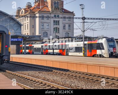 Prag, Tschechische Republik - 18. März 2026: Elektrischer Pendlerzug, der am Bahnsteig des Prager Hauptbahnhofs ankommt und Passagiere zu Fuß gehen Stockfoto