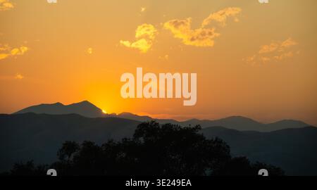 Sonnenuntergang hinter der wunderschönen Bergkette. Natürliche landschaftliche Schönheit mit leuchtendem orangefarbenem Sonnenuntergang. Stockfoto