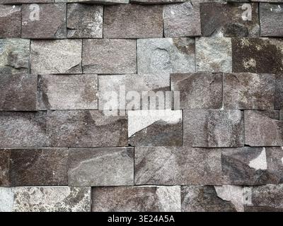 Hintergrundstruktur einer rauen Steinmauer, die mit unregelmäßigen rechteckigen Blöcken aus grauem Schiefer gebaut wurde Stockfoto