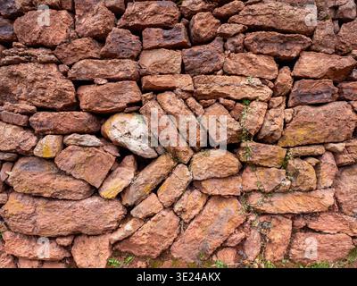 Eine Nahaufnahme einer traditionellen mediterranen Trockensteinmauer aus rohen Felsen. Diese natürliche Textur repräsentiert alte Mauerwerkstechniken, ländliche Ar Stockfoto