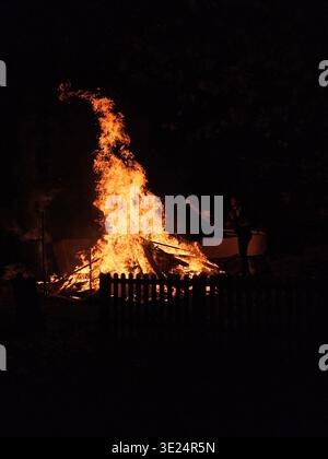 Ein glühendes Lagerfeuer erleuchtet den Nachthimmel in der Bonfire-Nacht, umgeben von glühender Glut, und fängt die Wärme und den festlichen Geist des Celebration ein Stockfoto
