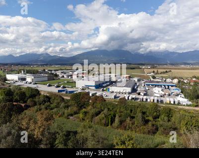 Lastkraftwagen laden tagsüber in einem großen Logistikzentrum, umgeben von Bergen und Feldern. Stockfoto