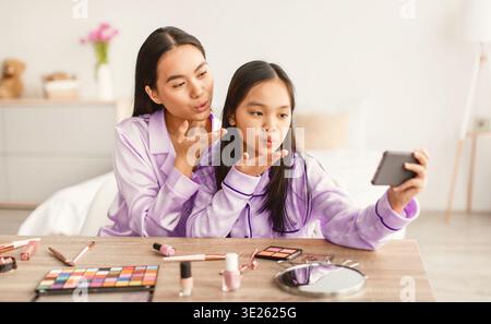 Mutter und Tochter nehmen Selfie, während sie am Nachmittag zusammen Make-up auftragen Stockfoto