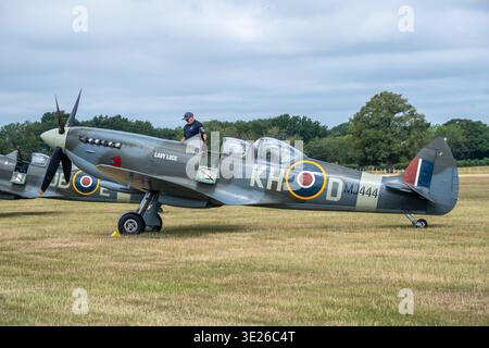 Headcorn Battle of Britain Airshow - Historic Supermarine Spitfire Warbird 'Lady Luck' (KH‑D MJ444) Taxis auf einem grasbewachsenen englischen Flugplatz mit Piloten Stockfoto