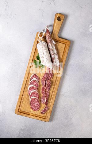 Auswahl an trocken gepökelten Gourmet-Salami, ganz und in Scheiben, serviert auf einem leichten Holzschneidebrett, mit traditionellem Wurstkonzept mit fr Stockfoto