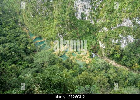 Semuc Champey, Guatemala - Luftlandschaft mit türkisfarbenen Terrassenpools und einem kleinen Wasserfall versteckt in einer üppigen tropischen Schlucht umgeben von dichten Stockfoto