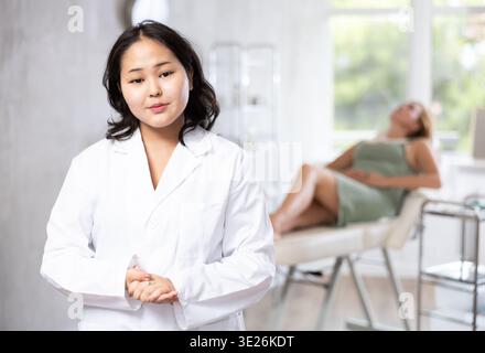 Asiatische professionelle Kosmetikerin, die Anti-Aging-Hautpflege für Patienten anpreist Stockfoto