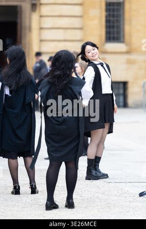Glücklicher Student, der ein akademisches Kleid trägt, lächelt während einer Zeremonie auf dem Campus Stockfoto