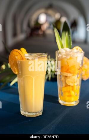 Leckerer Smoothie mit Mango-Papaya und Ananas im Glas, stehend auf dem Tisch mit schwachem Hintergrund. Stockfoto