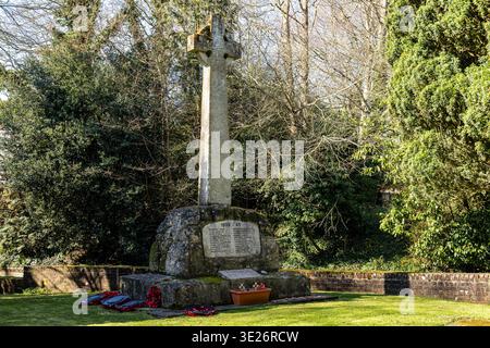 Ein steinernes Kriegsdenkmal-Kreuz mit eingravierten Namen zum Gedenken an die Soldaten des Weltkriegs in einem friedlichen Garten in der St. John the Baptist Church Pewsey Wilts Stockfoto