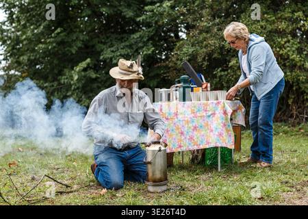 Seniorenpaar bereitet Tee im Freien zu und genießt ein rustikales Camping-Erlebnis in der Natur Stockfoto