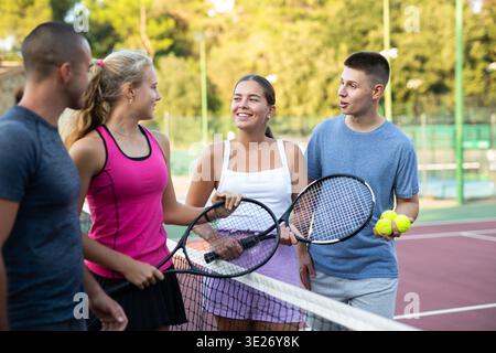 Vier Tennisspieler stehen auf dem Platz und reden über Match Stockfoto
