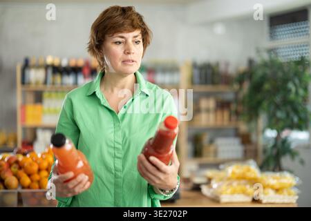 Erwachsene Frau, die Säfte wählt Stockfoto