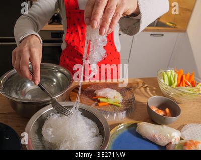 Zubereitung frischer vietnamesischer Frühlingsrollen mit Reispapier, Reisnudeln, Gemüse und Garnelen in einer Küche. Stockfoto