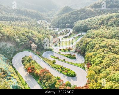 Atemberaubende Drohnenaufnahmen von Boeuns Maltijae Pass. Zwölf sich windende Serpentinen bei Sonnenuntergang mit goldenem Licht über bewaldeten Bergen. Authentische koreanische Straße t Stockfoto