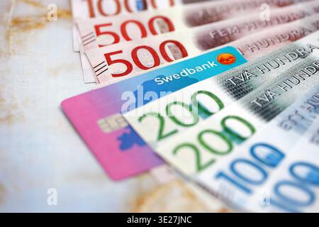 KIEW, UKRAINE - 28. JANUAR 2026 Schwedbank-Karte und schwedische Kronen-Geldscheine auf dem Tisch in Nahaufnahme. Swedbank ist die beliebteste Bank in Schweden Stockfoto