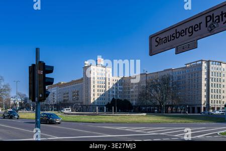 Blick auf den Strausberger Platz in Berlin mit Straßenschild im Vordergrund und klassischer sozialistischer Architektur der Karl-Marx-Allee im Hintergrund. Stockfoto