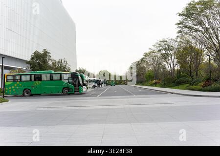 Grüne Busse parkten auf einer modernen Stadtstraße in der Nähe eines eleganten Gebäudes in Shanghai, China – breite Straße gesäumt Stockfoto