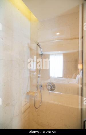 Moderne Marmordusche mit Glasgehäuse in luxuriösem Hotelbad mit Ambientebeleuchtung und Stockfoto