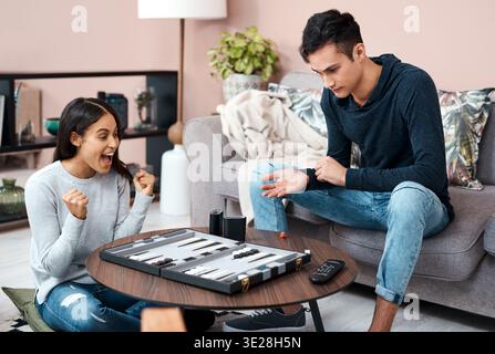 Aufgeregt, schreiend oder paarweise mit Brettspiel in der Lounge, Gewinnstrategie oder Wettbewerbspartner für den Kampf. Schreien, feiern oder Leute mit Backgammon Stockfoto