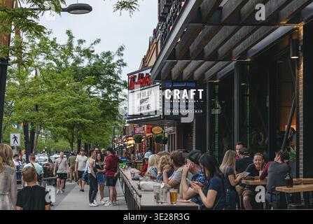 Die Leute sitzen auf der Terrasse des Cafés im Freien. Touristen und Einheimische genießen Speisen und Getränke im Freien in einem The Street Food Restaurant in Kelowna Stockfoto