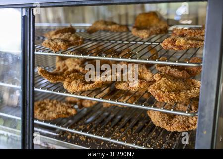 Goldenes gebratenes Huhn auf Metallgestell in der Vitrine. Knuspriges paniertes Fleisch in wärmer sieht appetitlich aus und weckt Hunger und tiefe sa Stockfoto