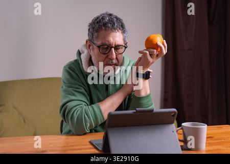 Konzentrierter Senior-Mann, der ein Tablet zu Hause während einer täglichen digitalen Routine am Morgen verwendet. Stockfoto