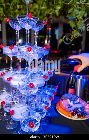 Schaumwein wird in eine mehrstufige Glaspyramide gegossen. Es ist ein festliches Ritual für Gäste. Konzept von Premium Social Event, Luxus Lifestyle Cell Stockfoto